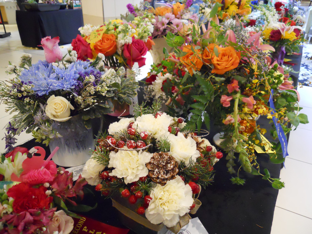 A great number of colorful bouquets are displayed on a black table. The colors violet, red, orange, pink, and green pop out against a white interior.